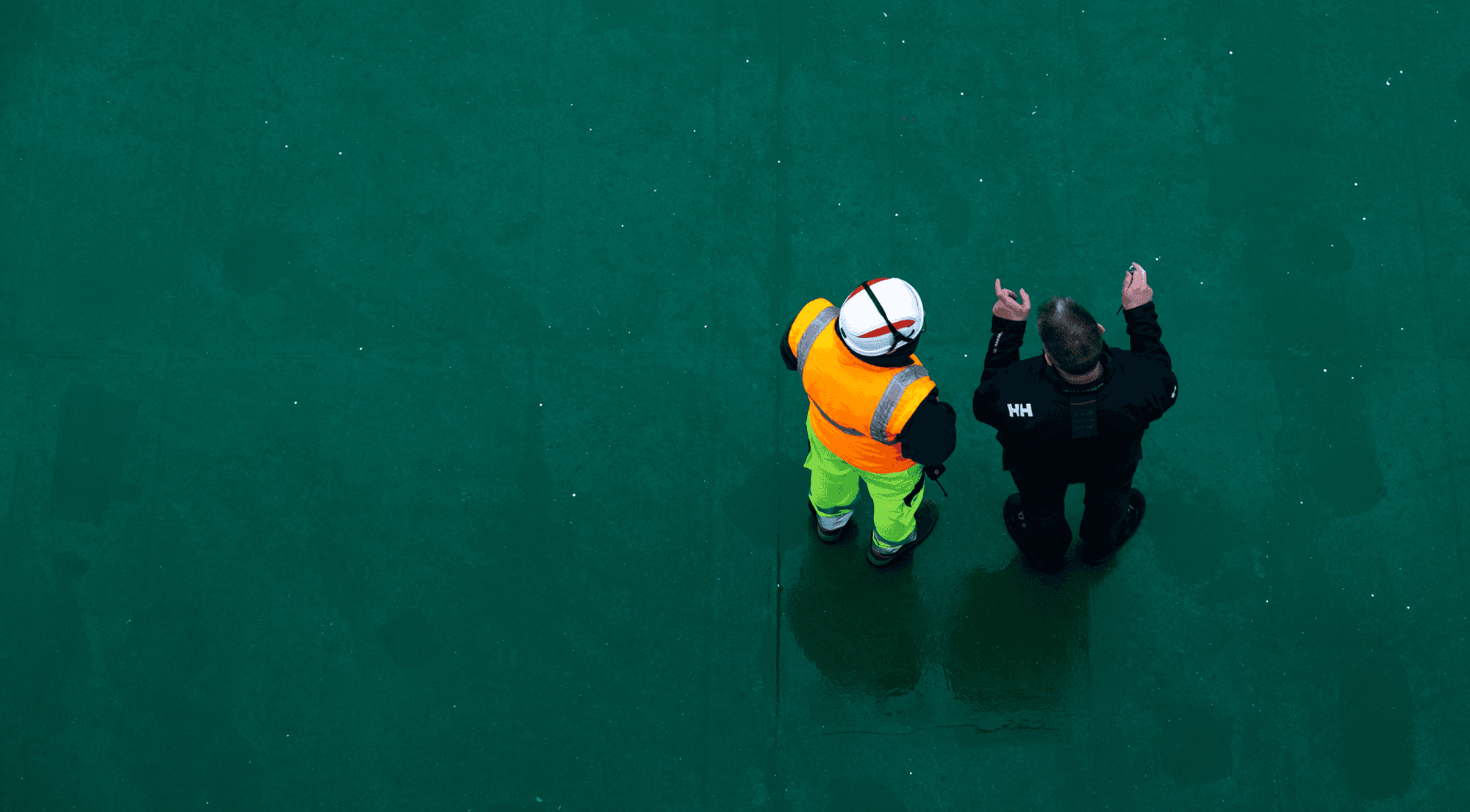 Bird's eye view of two DFDS workers on a green surface of a freight ship.
