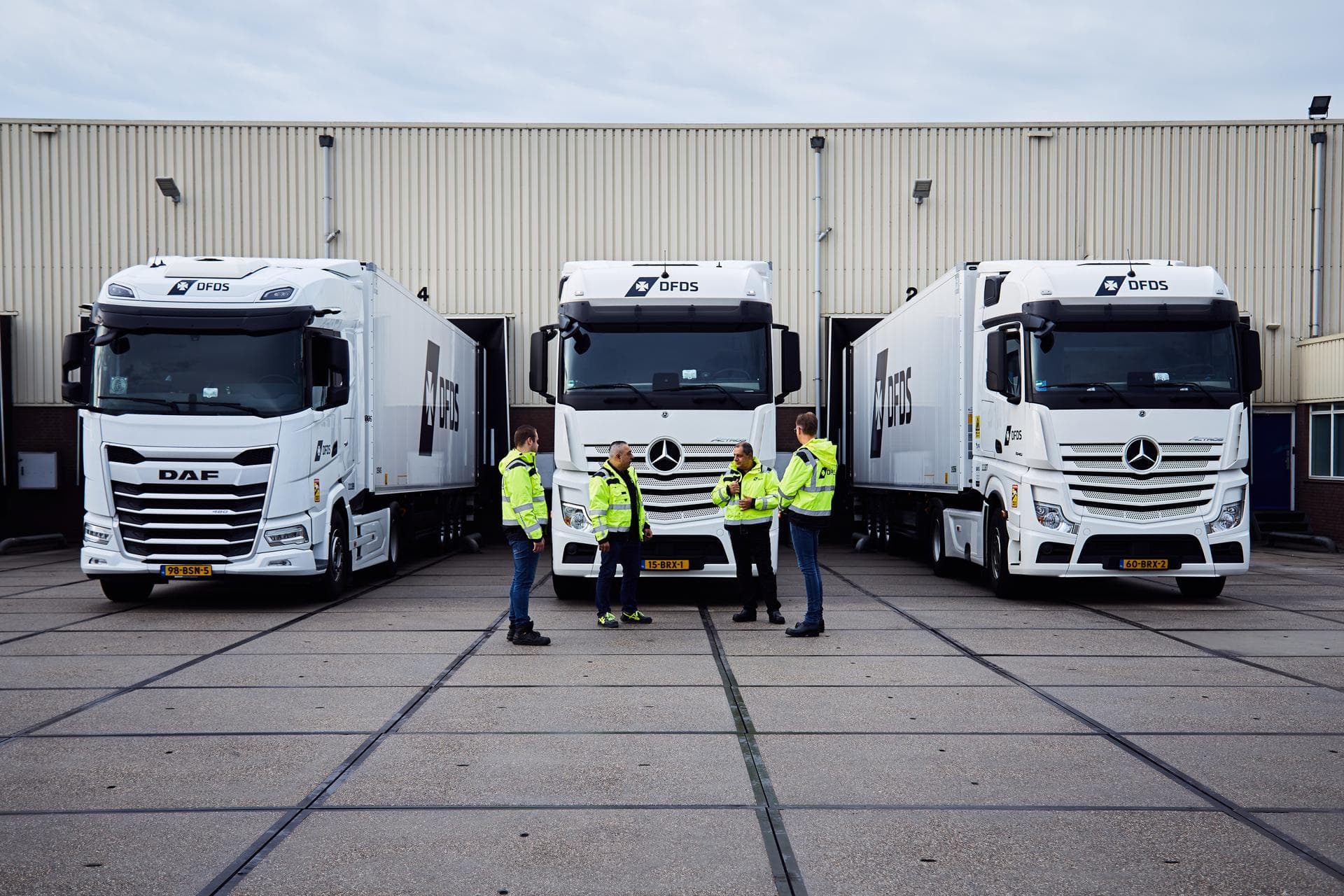 Drivers standing and talking in front of DFDS reefer trucks.